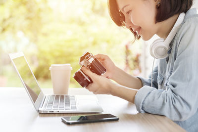 Midsection of woman using mobile phone while sitting on table