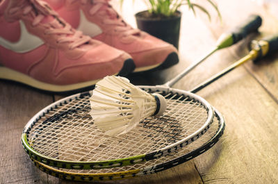 High angle view of rackets with shuttlecock and sports shoes on hardwood floor