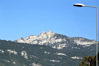 Low angle view of snowcapped mountains against clear blue sky