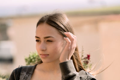 Caucasican teenager on a blurred background. long hair bwith a black shirt in a sunny day