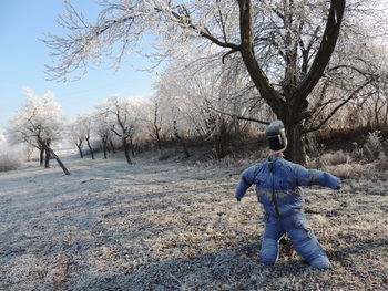 Rear view of man standing on bare tree