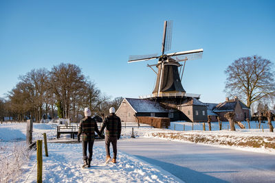 Rear view of people on snow covered field