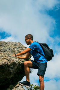 Man standing on rock against sky