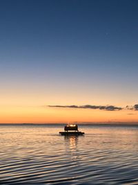 Boat sailing on sea against sky during sunset