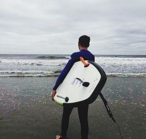 Full length of man playing at beach against sky