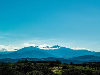 Scenic view of mountains against blue sky