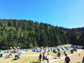 Panoramic view of people on landscape against clear blue sky