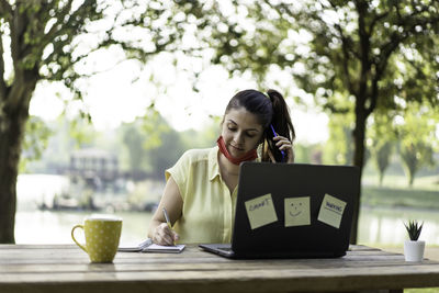 Portrait of woman using phone while sitting on table