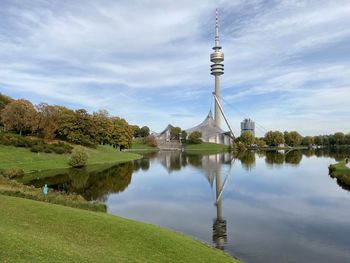 Reflection of tower in lake against cloudy sky