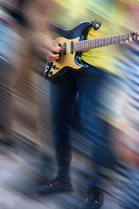 Blurred motion of man playing guitar on street