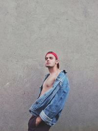 Side view portrait of man standing against wall