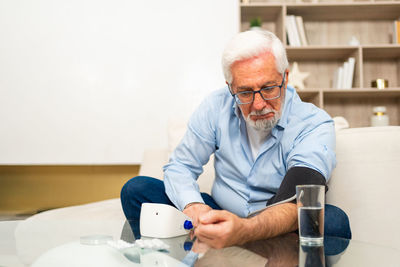 Portrait of senior man using mobile phone while sitting against white background