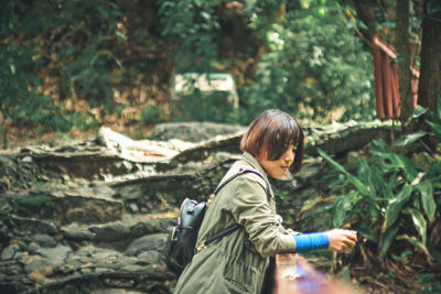 Side view of woman standing in forest