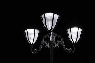 Low angle view of illuminated lamp against black background