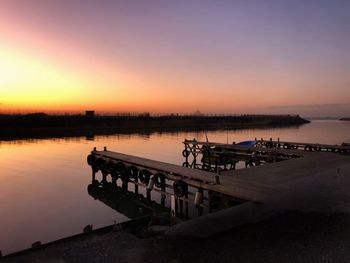 Pier over lake against sky during sunset