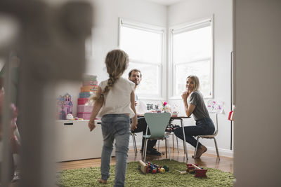 Parents looking at girl walking towards them in playroom