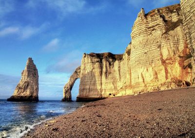 Rock formations on beach against sky