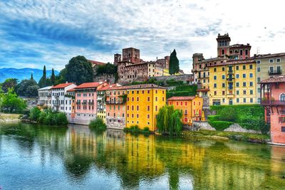 Buildings by river against sky