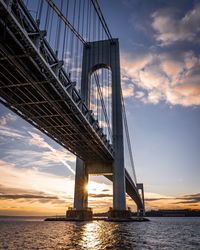 Low angle view of bridge over river against cloudy sky