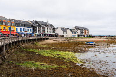 Houses by river against sky in city