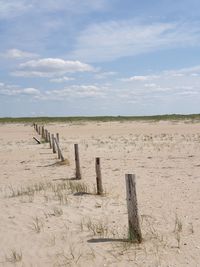 Wooden posts on field against sky