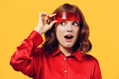 Portrait of young woman against yellow background