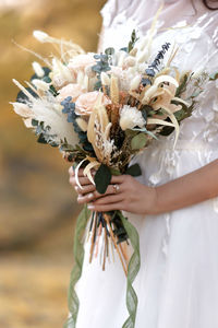 Midsection of bride holding bouquet