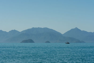 Scenic view of sea and mountains against clear sky