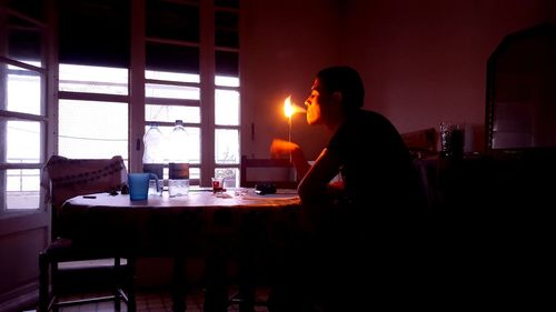 Side view of man sitting at restaurant table at home