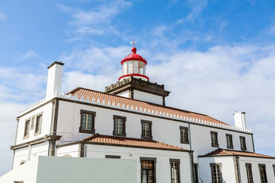  low angle view of lighthouse by building against sky