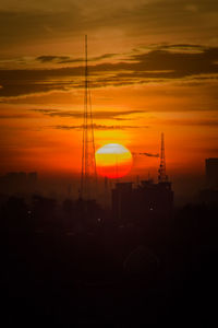 Silhouette buildings against orange sky