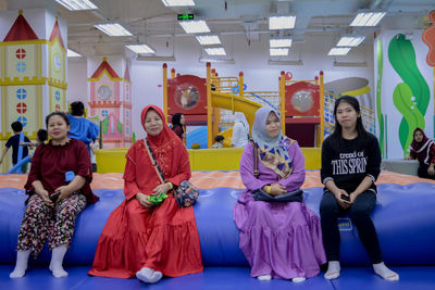 Full length portrait of women sitting in corridor