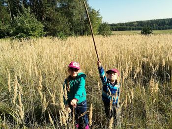 Portrait of children standing on field against trees