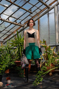 Full length of young woman standing against plants