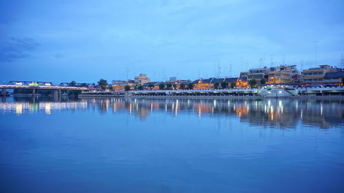 Reflection of buildings in lake against blue sky