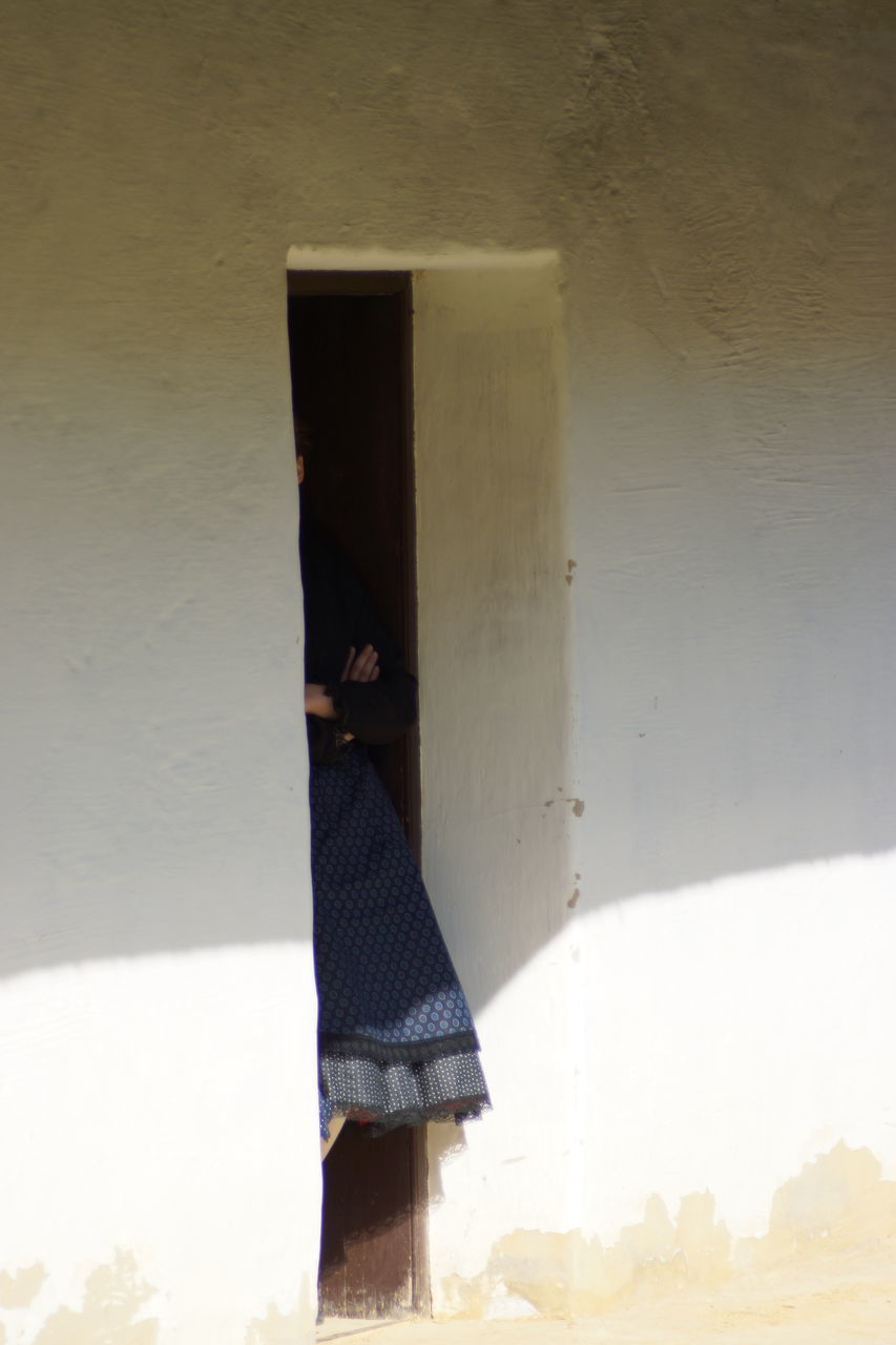 LOW SECTION OF WOMAN STANDING IN FRONT OF BUILT STRUCTURE