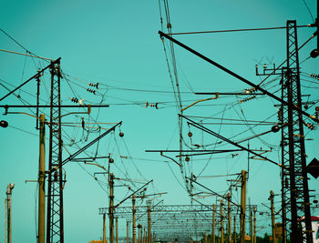 Low angle view of electricity pylon against clear blue sky