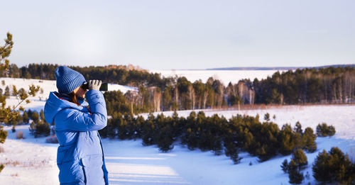 Rear view of woman standing on snow covered landscape