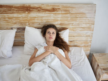 Portrait of young woman sitting on bed at home