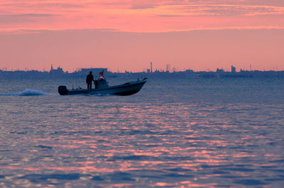Silhouette man on boat in sea against sky during sunset