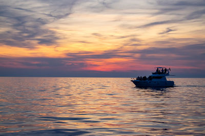 Boat sailing in sea against sky during sunset
