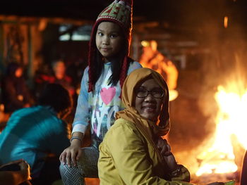 Portrait of mother with daughter by campfire at night