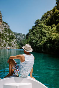 Rear view of man sitting on boat against trees