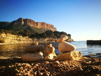 Rocks by sea against clear sky