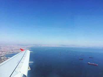 Airplane flying over sea against clear blue sky