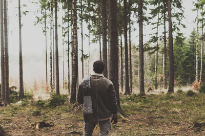 Rear view of young man standing in forest