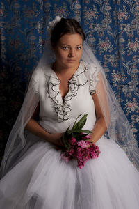 Portrait of beautiful young woman standing against white wall