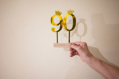 Cropped hand of person holding heart shape against wall