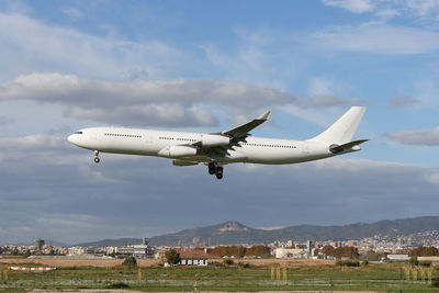 Airplane flying over landscape against sky