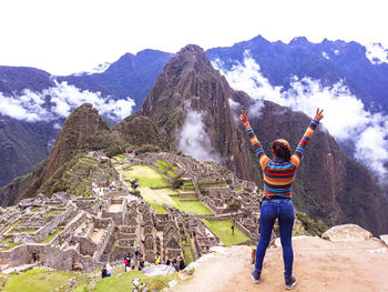 Rear view full length of woman with arms raised standing at machu picchu